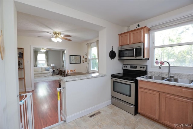 kitchen with ceiling fan, appliances with stainless steel finishes, a sink, open floor plan, and visible vents