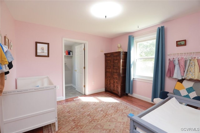 bedroom with light wood-style floors, baseboards, and a spacious closet