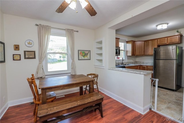 kitchen featuring a peninsula, appliances with stainless steel finishes, a wealth of natural light, and ceiling fan