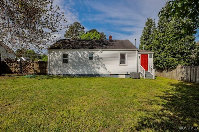 rear view of house with entry steps, a fenced backyard, a yard, and central AC
