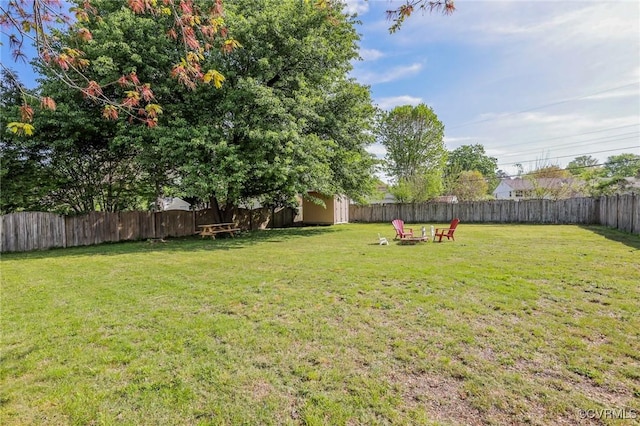 view of yard with a fenced backyard, an outbuilding, a storage shed, and an outdoor fire pit