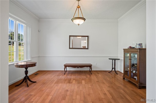 sitting room featuring light wood-style flooring, crown molding, and baseboards