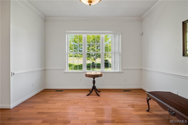 empty room featuring baseboards, visible vents, light wood-style floors, and ornamental molding