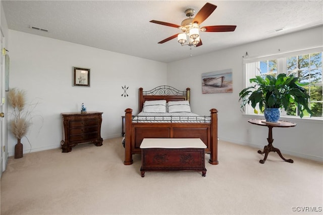 carpeted bedroom with a textured ceiling, visible vents, baseboards, and ceiling fan