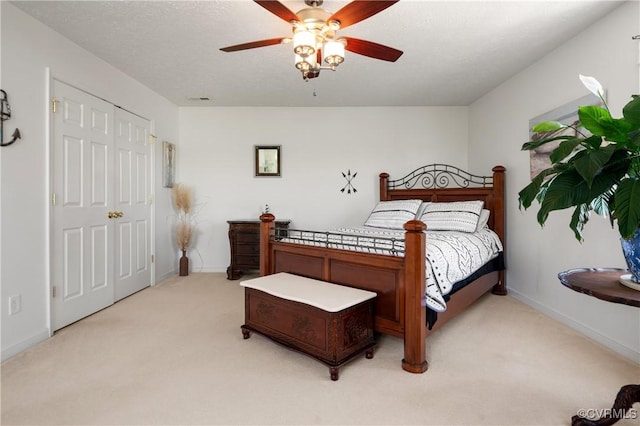 bedroom featuring visible vents, a ceiling fan, a closet, baseboards, and light colored carpet