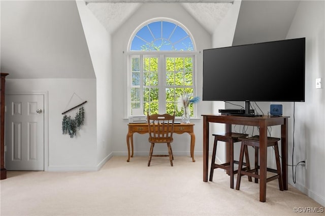 office space with baseboards, vaulted ceiling, a healthy amount of sunlight, and light carpet