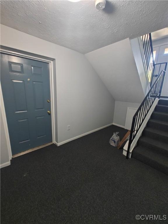 bonus room featuring dark colored carpet, baseboards, and stairs