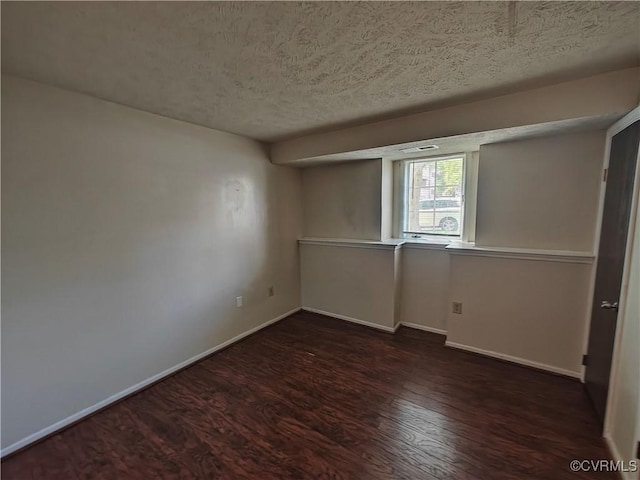 empty room featuring dark wood-style floors, baseboards, and a textured ceiling