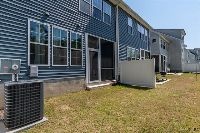 back of house with cooling unit and a lawn