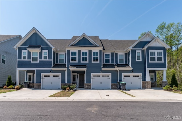 view of front of property with driveway, stone siding, an attached garage, and board and batten siding