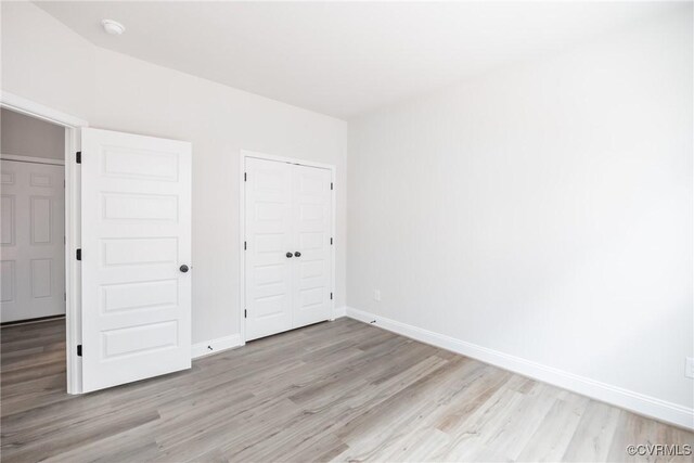 unfurnished bedroom featuring baseboards, light wood-style floors, and a closet