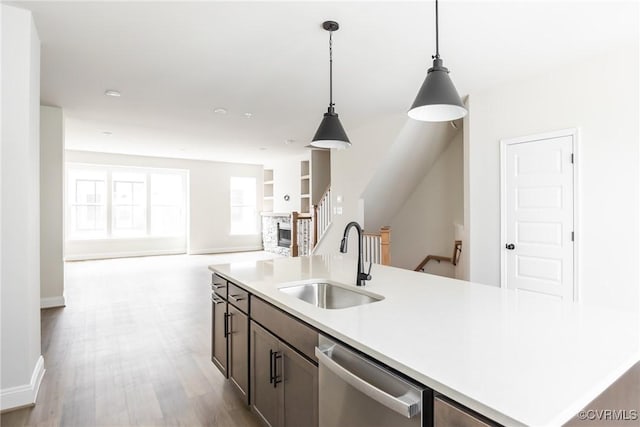 kitchen featuring decorative light fixtures, light countertops, dishwasher, a sink, and open floor plan