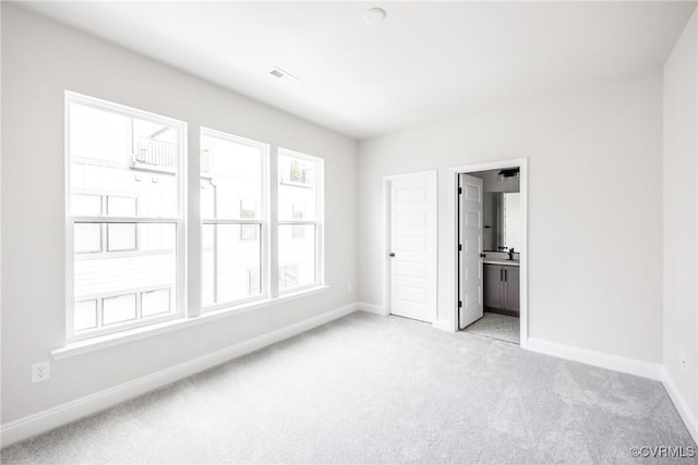 unfurnished bedroom featuring baseboards, visible vents, light carpet, and connected bathroom