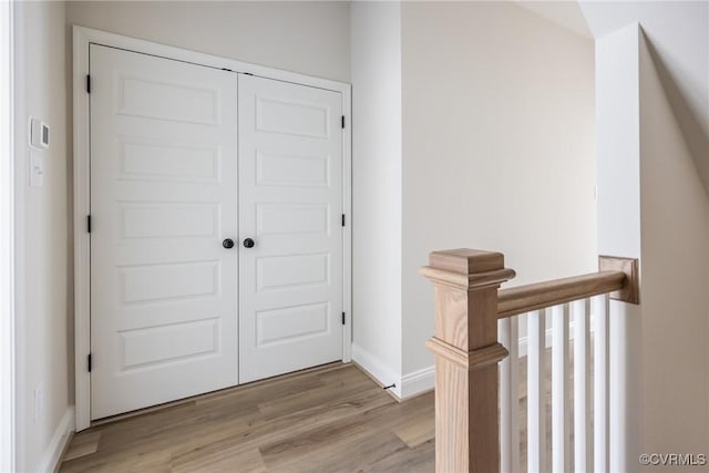 interior space featuring baseboards, light wood-type flooring, and an upstairs landing
