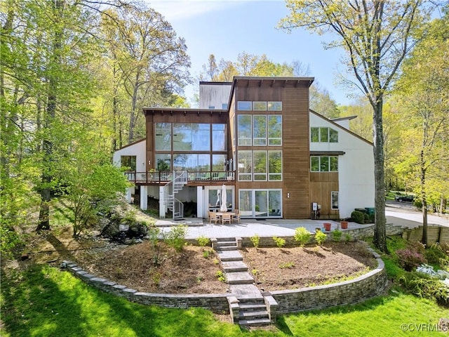rear view of property with a sunroom, a patio area, a wooden deck, and stairway