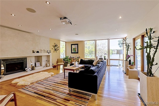 living area featuring a fireplace with raised hearth, recessed lighting, and light wood finished floors