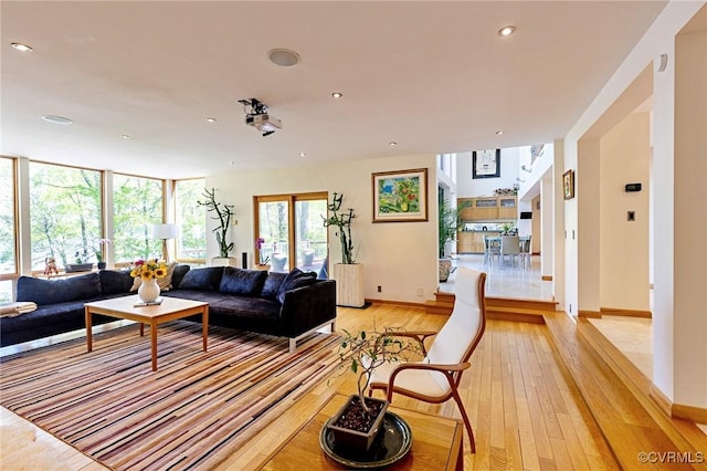 living area featuring recessed lighting, baseboards, and light wood-type flooring