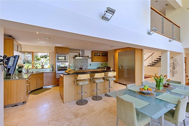 kitchen with built in appliances, modern cabinets, wall chimney exhaust hood, a sink, and a warming drawer
