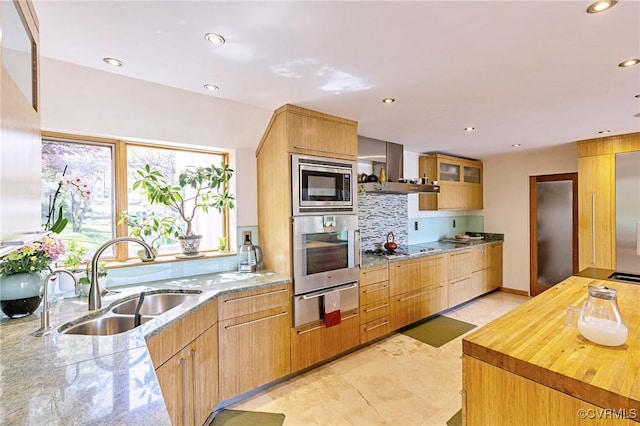 kitchen featuring appliances with stainless steel finishes, a sink, wall chimney exhaust hood, recessed lighting, and a warming drawer