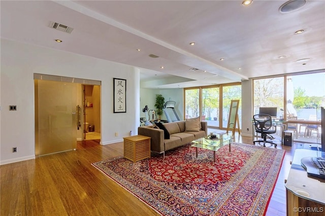 living room with baseboards, visible vents, floor to ceiling windows, and wood finished floors