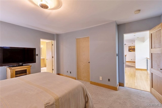 carpeted bedroom featuring connected bathroom and baseboards