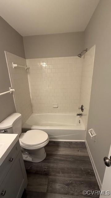 full bathroom with wood finished floors, toilet, vanity, baseboards, and tub / shower combination