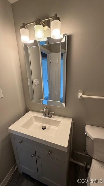 half bath featuring vanity and toilet