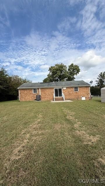 back of property featuring a yard, entry steps, and brick siding