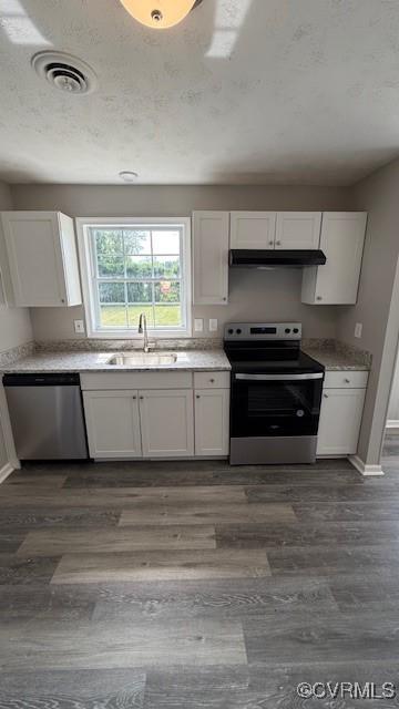 kitchen featuring under cabinet range hood, appliances with stainless steel finishes, white cabinetry, and a sink
