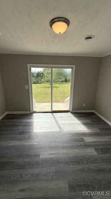 spare room with wood finished floors, visible vents, and baseboards