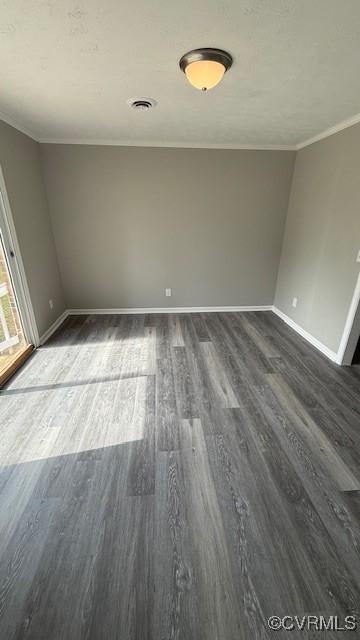 spare room featuring dark wood-type flooring, baseboards, visible vents, and crown molding