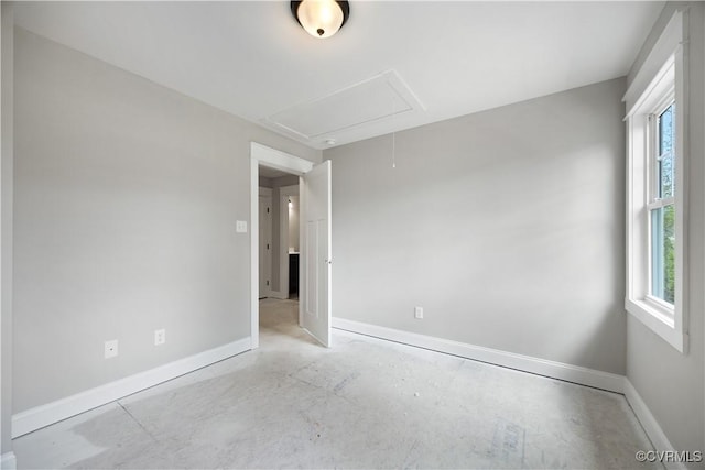 unfurnished room featuring attic access, baseboards, and plenty of natural light