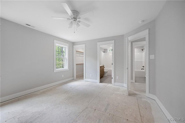 unfurnished bedroom featuring connected bathroom, a closet, a ceiling fan, visible vents, and a walk in closet
