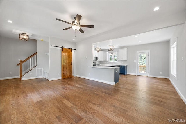 unfurnished living room featuring recessed lighting, a barn door, ceiling fan, and wood finished floors