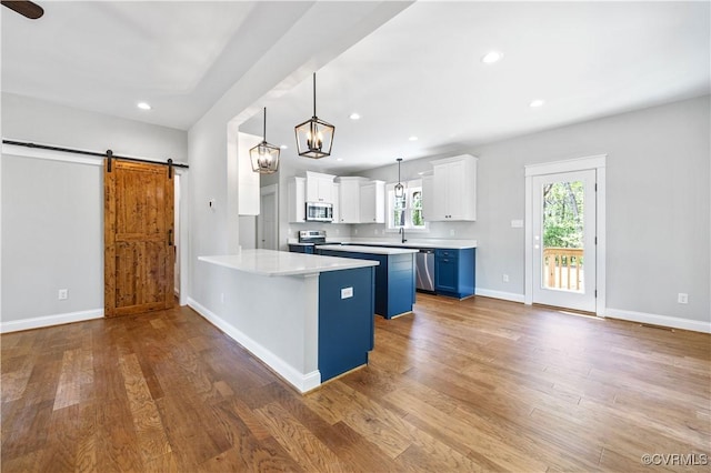 kitchen with a peninsula, white cabinets, a barn door, appliances with stainless steel finishes, and light countertops
