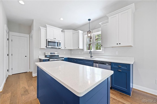 kitchen with light wood-type flooring, a sink, blue cabinetry, and stainless steel appliances