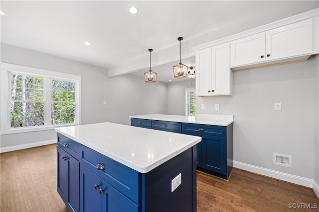 kitchen featuring blue cabinets, wood finished floors, and baseboards