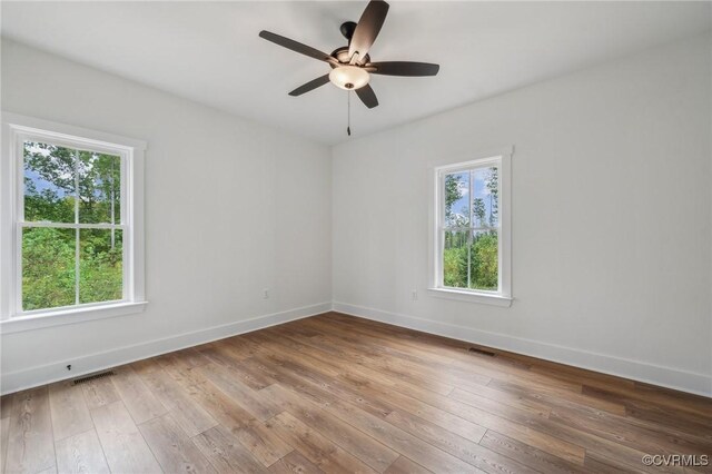 empty room with visible vents, baseboards, a ceiling fan, and hardwood / wood-style floors