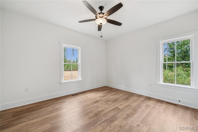 spare room with light wood finished floors, baseboards, and visible vents