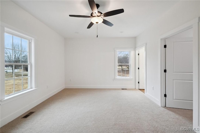 spare room featuring light carpet, visible vents, and plenty of natural light