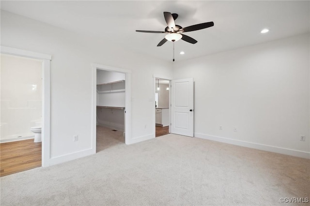 unfurnished bedroom featuring baseboards, a walk in closet, and carpet floors