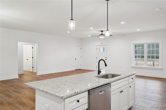 kitchen with pendant lighting, dishwasher, a sink, open floor plan, and baseboards