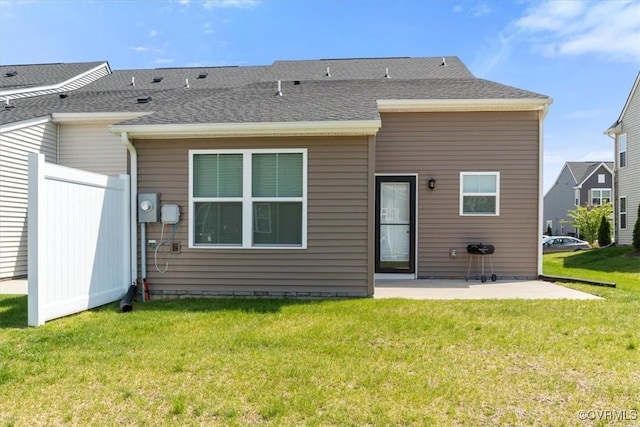 back of house with a lawn, roof with shingles, and a patio area