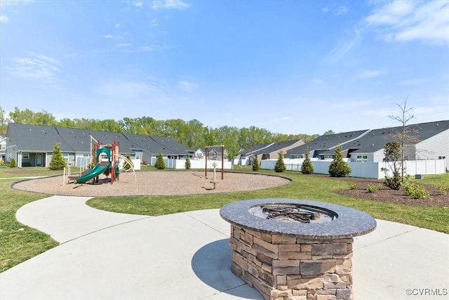 communal playground with a fire pit, fence, a residential view, and a lawn