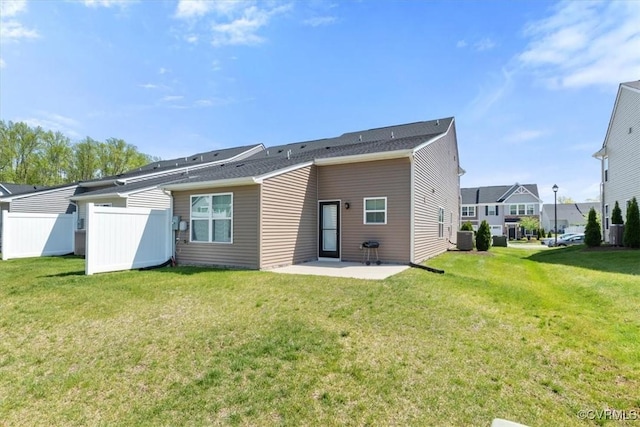 rear view of house featuring central air condition unit, fence, a yard, and a patio