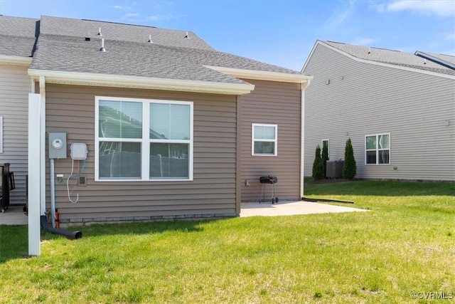 back of house featuring a patio area, a shingled roof, and a yard