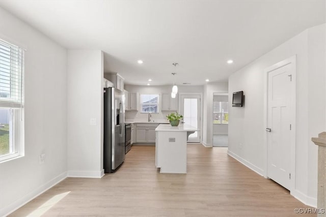 kitchen with light wood-style flooring, a wealth of natural light, a sink, stainless steel fridge with ice dispenser, and light countertops