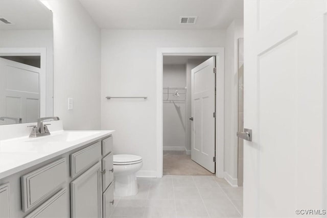bathroom featuring a spacious closet, visible vents, toilet, vanity, and baseboards