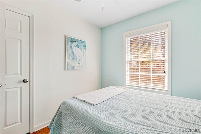 bedroom featuring baseboards, wood finished floors, and multiple windows