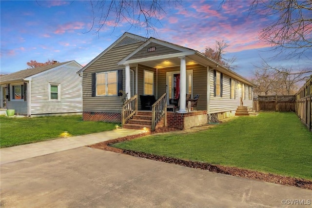 view of front of property featuring a lawn, fence, and covered porch